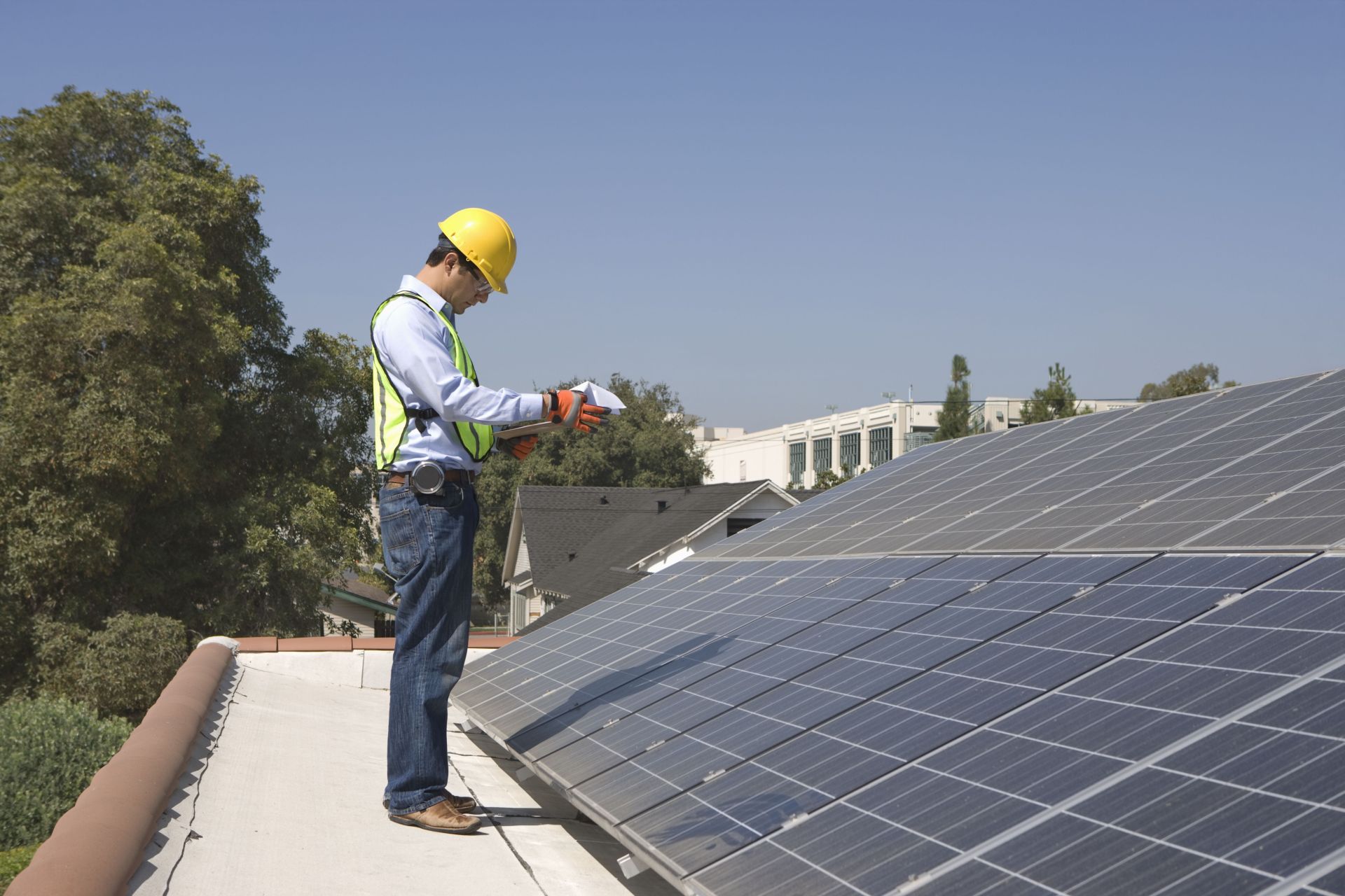 Ein Mann mit gelbem Helm steht vor Reihen mit Solarpaneelen.