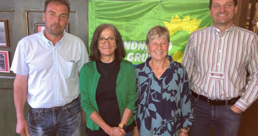 4 Menschen stehen vor einer GRÜNEN Flagge